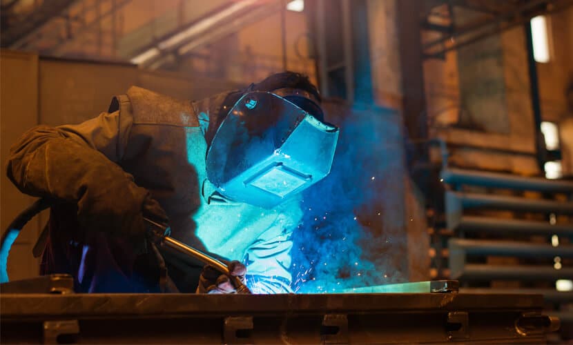 A custom fabrication professional welding a large-scale art piece
