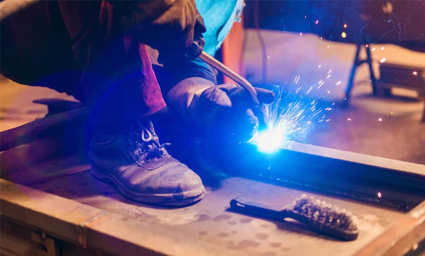 A custom fabrication professional is welding pieces of metal