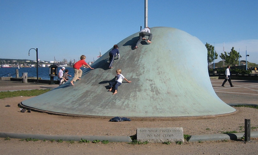 A group of children are playing on top of a large public art project in the park